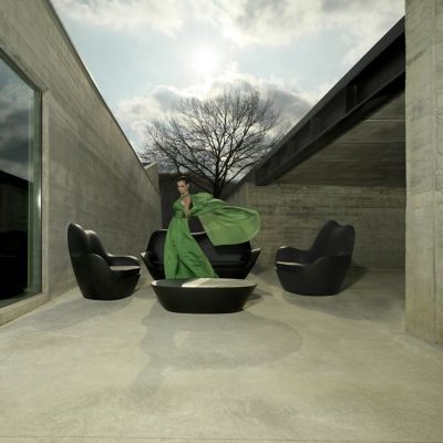 Dark outdoor lounge chairs and coffee table in a modern architectural setting.